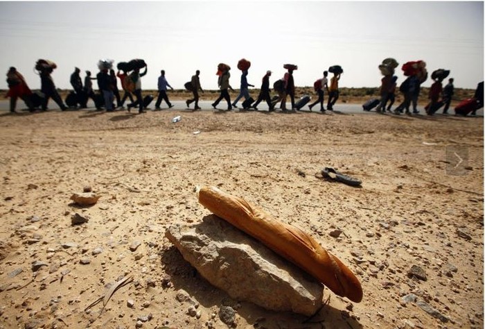 Dòng người mang theo đồ đạc đi bộ qua khu vực biên giới giữa Libya – Tunisia, đến một trại tị nạn của United Nations High Commissioner for Refugees (UNHCR) để thoát khỏi nạn bạo lực ở Libya. Tác giả: Yannis Behrakis.